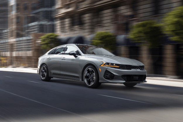 2022 Kia K5 Driving Down A Street Three-Quarter View