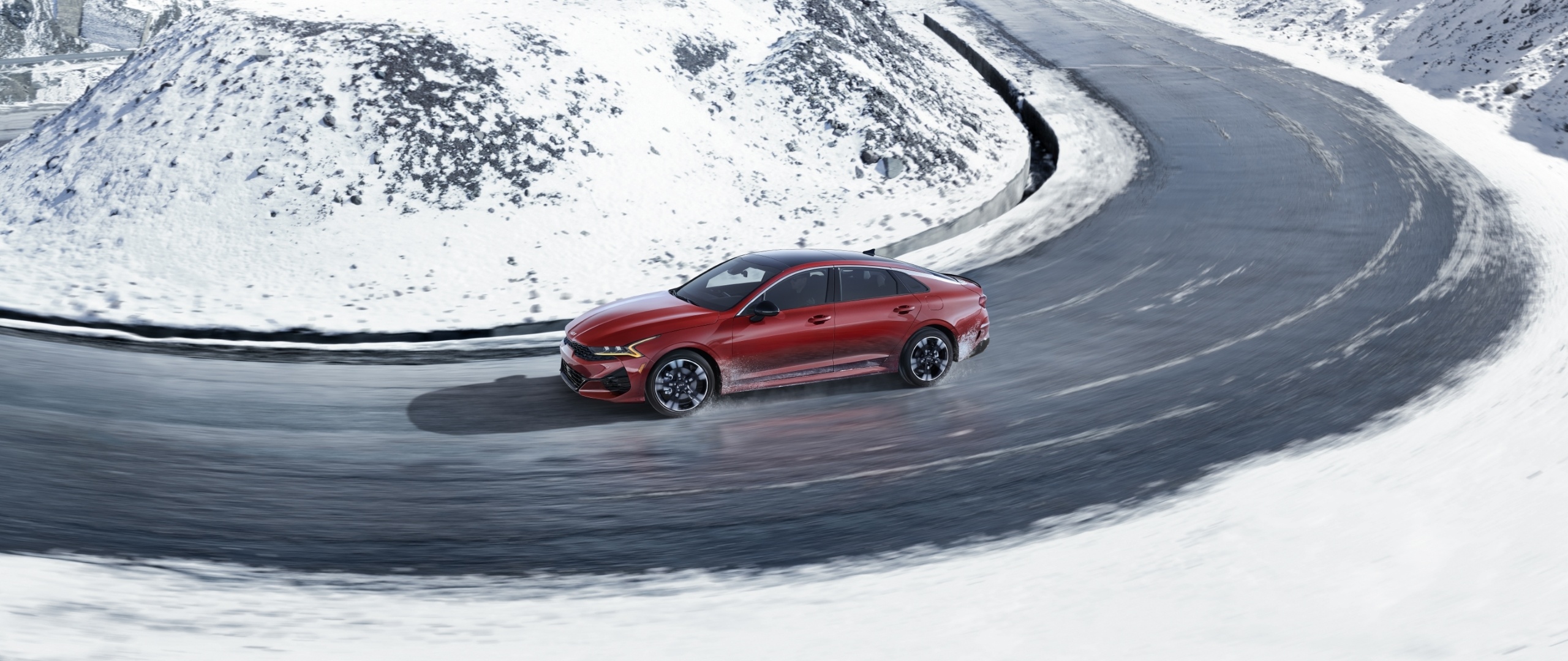 2023 Kia K5 Driving On A Snowy Mountain Road With Available AWD Side View