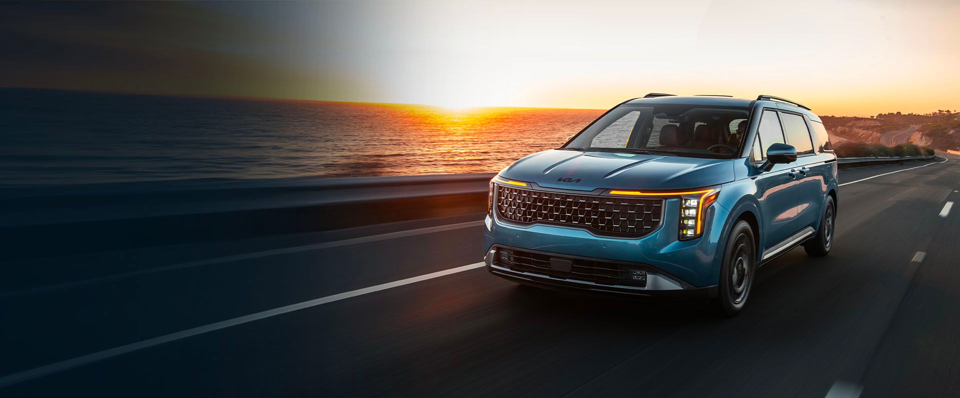 2027 Kia Carnival MPV front three-quarter view in a scenic outdoor setting