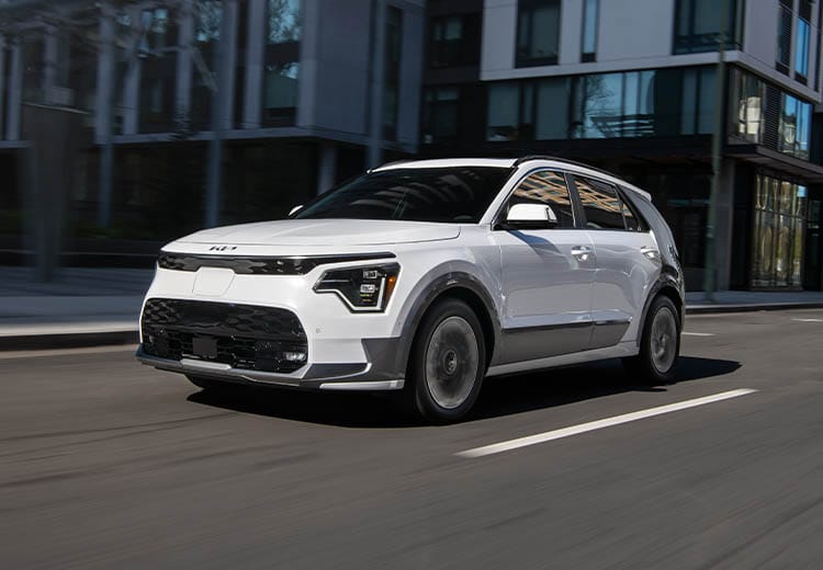 2026 Kia Niro EV in white driving on a city road, front three-quarter view