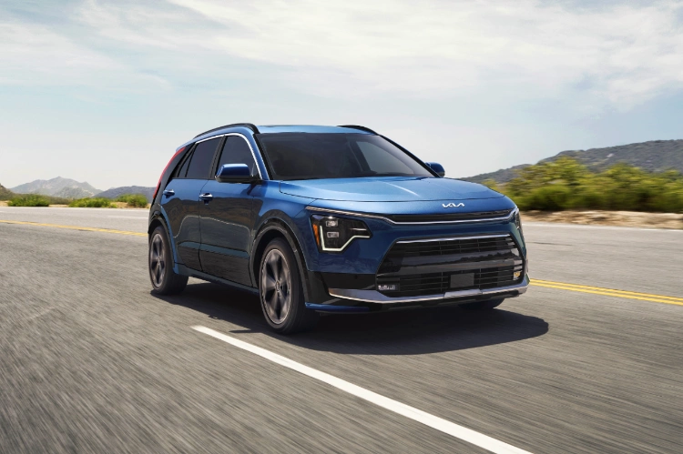 2023 Niro PHEV in blue, 3-quarter front view action shot while driving down a mountain road.