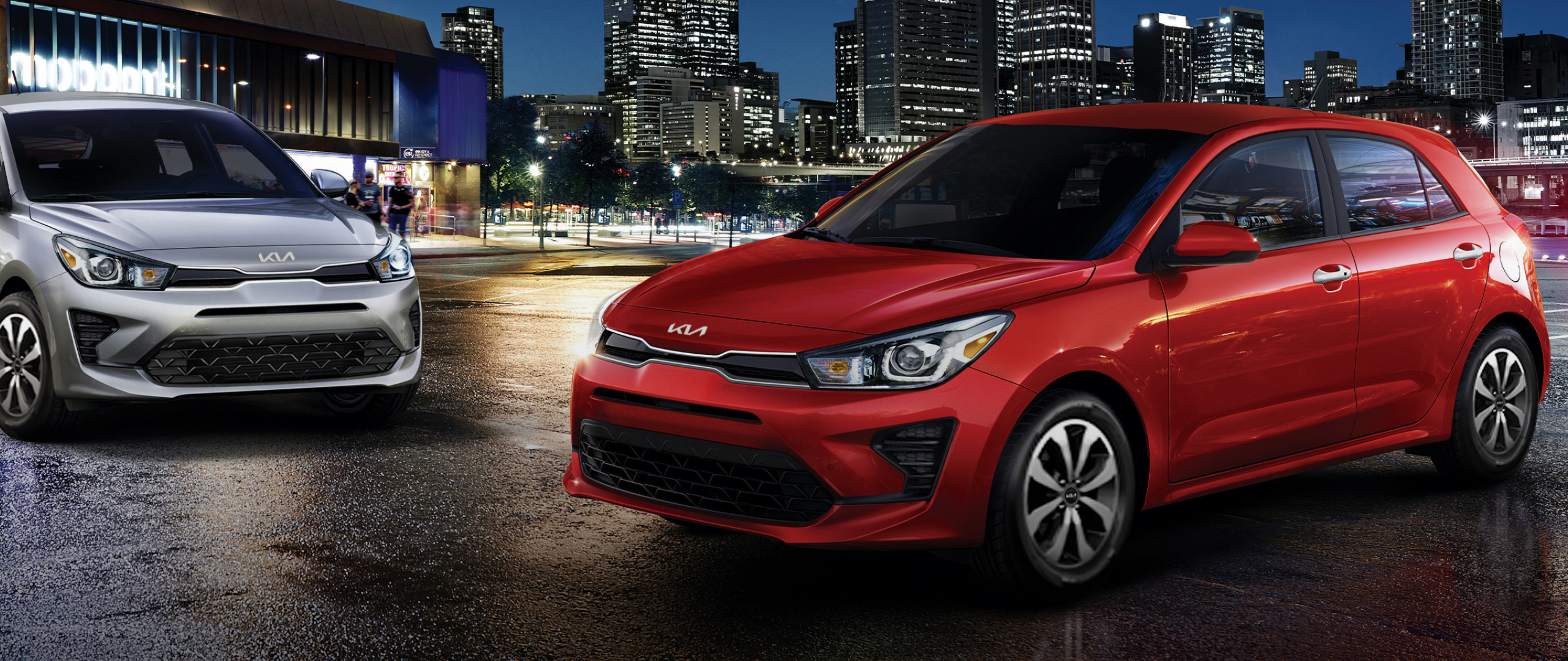 2022 Kia Rio 5-Door Red And Silver Vehicles Parked In Front Of A City At Night