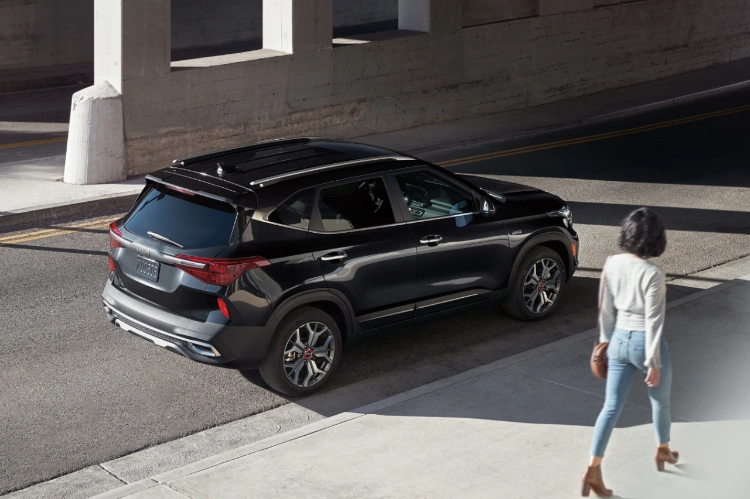 2022 Kia Seltos Passing A Woman In The Foreground Rear Three-Quarter View