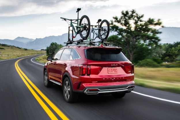 2022 Kia Sorento Hybrid Driving Down A Winding Road With A Bike Rack Equipped Rear Three-Quarter View