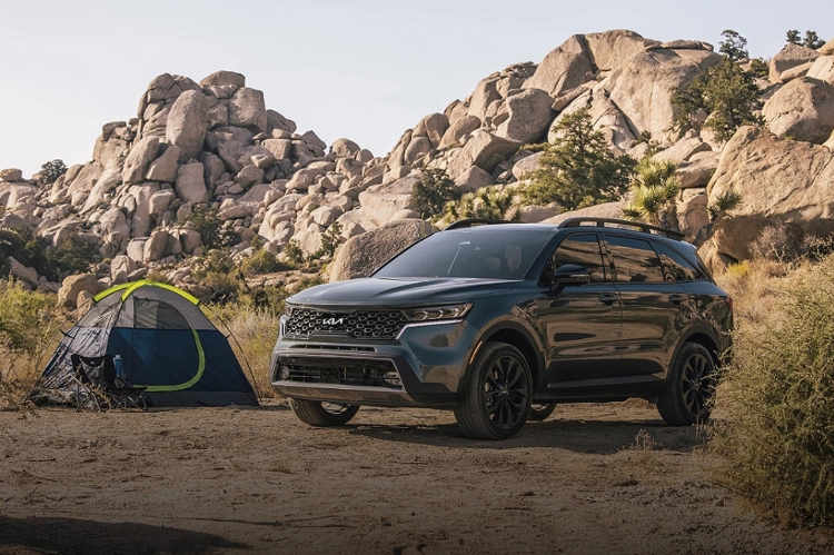 2023 Kia Sorento Parked In Front Of A Tent And Two Large Rocky Mountains
