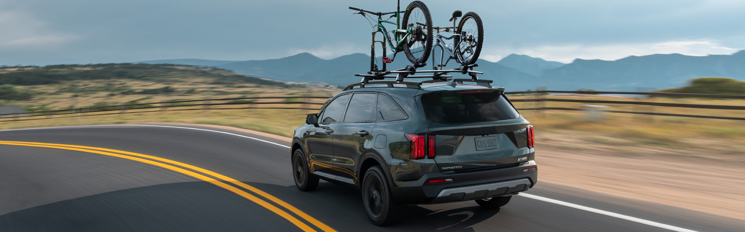 2023 Kia Sorento Driving On An Open Road With A Bike Rack Equipped Rear Three-Quarter View