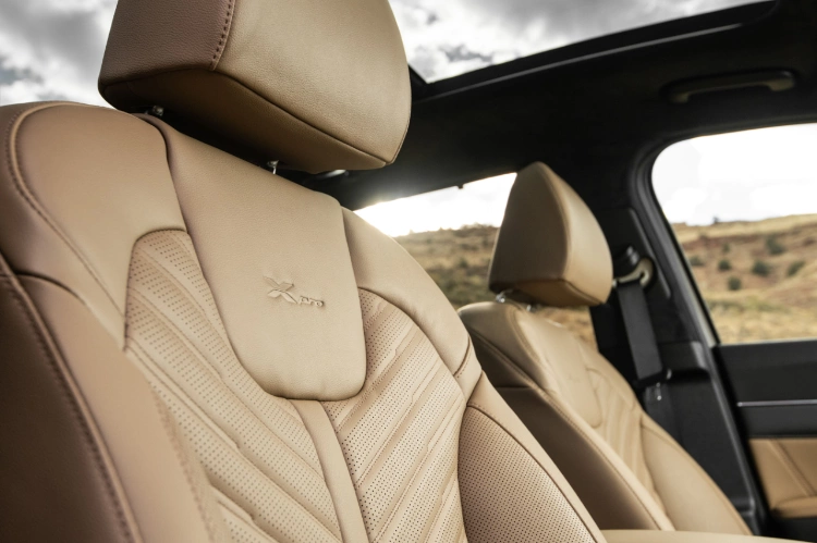 Vista ampliada del interior del Kia Sorento 2024 con asiento del pasajero de cuero marrón con detalles de chebrón y el emblema “X-Pro”