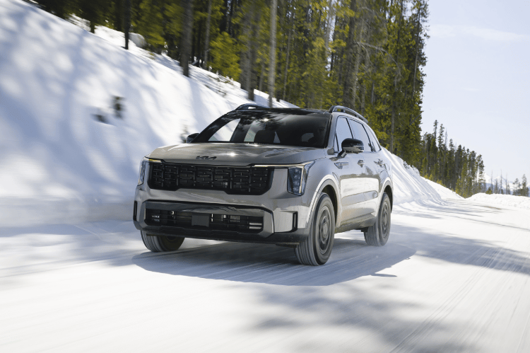 2025 Kia Sorento, three-quarter front view, driving on a snowy road in the mountains