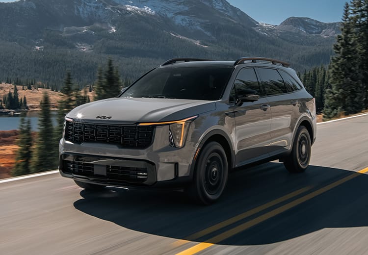 2026 Kia Sorento, three-quarter driver's side view, driving on a road by the lake in the mountains
