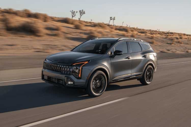 Vehículo Sportage 2026 en vista tres cuartos frontal, circulando por un camino desértico