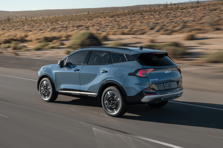 Vehículo Sportage 2026 en vista tres cuartos trasera, circulando por un camino desértico.