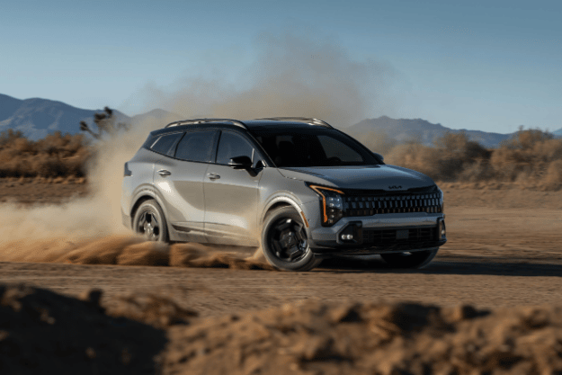 Vehículo Sportage 2026 en vista tres cuartos frontal, realizando un giro pronunciado en terreno desértico, creando una gran nube de polvo detrás de él