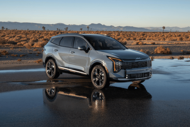 Vehículo Sportage 2026 en vista tres cuartos frontal, estacionado sobre un camino mojado en el desierto