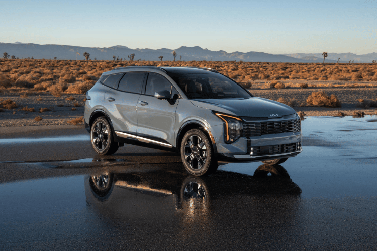 Vehículo Sportage 2026 en vista tres cuartos frontal, estacionado sobre un camino mojado en el desierto