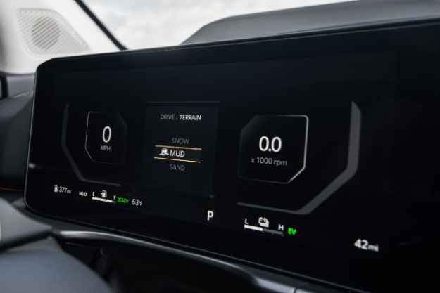 Vista tres cuartos del tablero digital que muestra el velocímetro a la izquierda, las opciones de modo de terreno en el centro y el tacómetro a la derecha