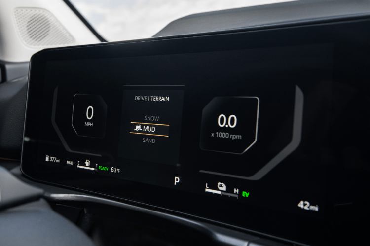 Vista tres cuartos del tablero digital que muestra el velocímetro a la izquierda, las opciones de modo de terreno en el centro y el tacómetro a la derecha