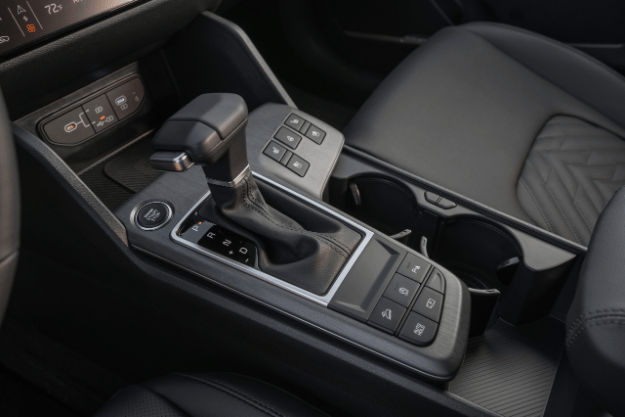 Interior del vehículo Sportage 2026, vista ampliada de la consola central con la palanca de cambios con patrón en zig-zag