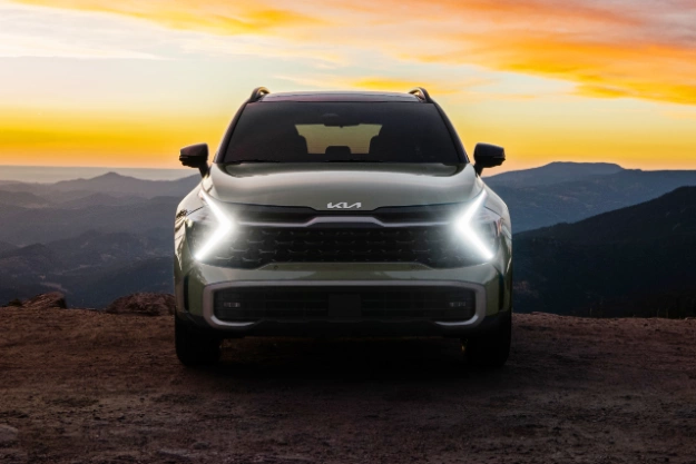 2024 Kia Sportage Parked On A Hill Peak WIth LED Headlights Turned On At Sunset Front-View