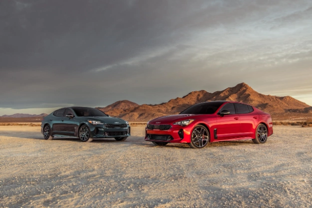2023 Kia Stinger Vehicles Parked On Rocky Terrain In Front Of Mountains Three-Quarter View