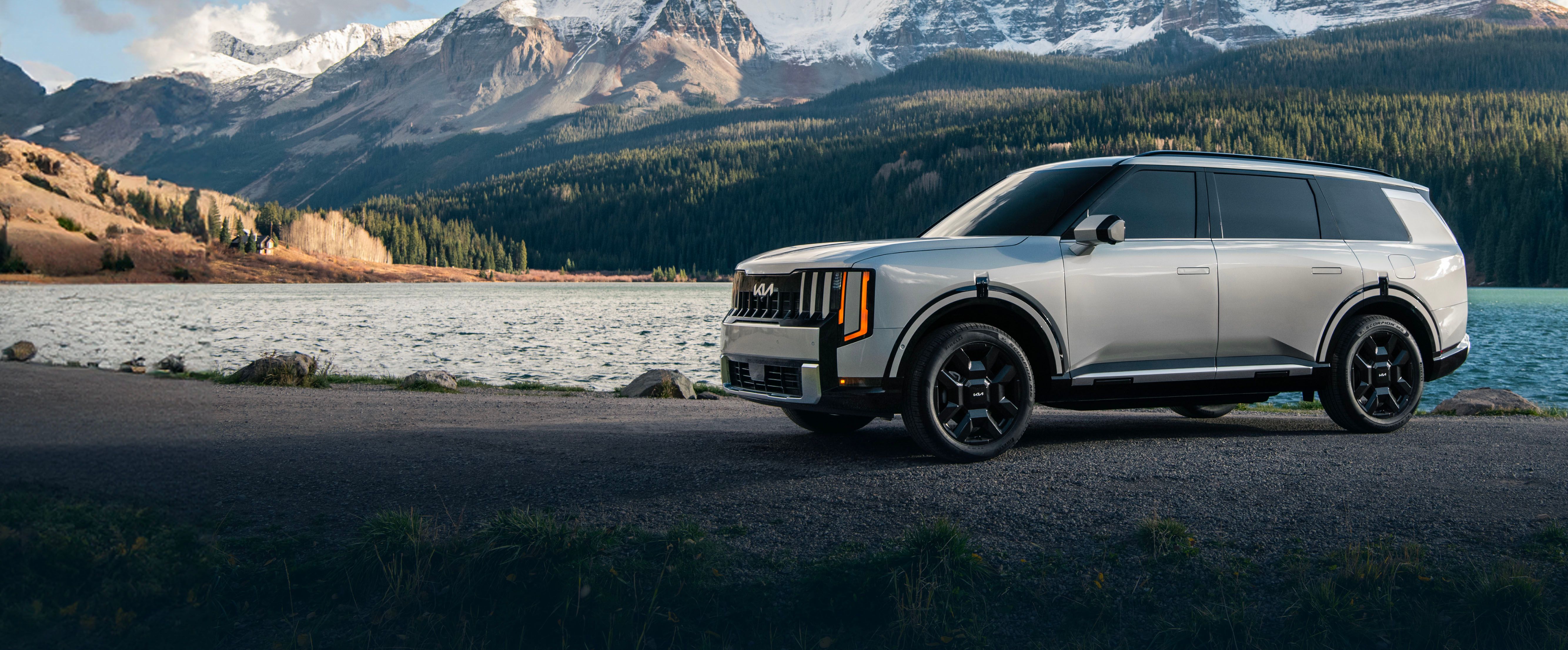 2027 Kia Telluride Turbo-Hybrid parked lakeside with mountains in the background