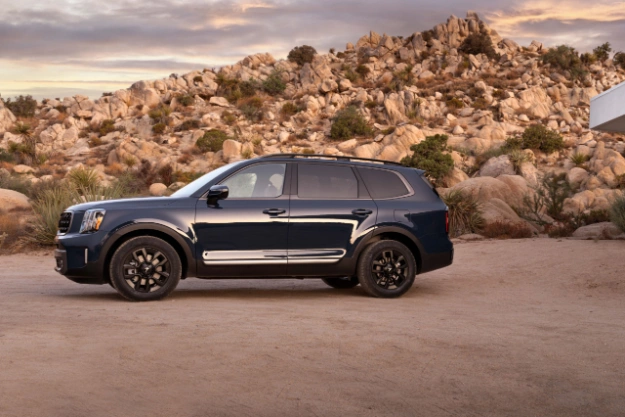 2023 Kia Telluride Parked In Front Of A Large Rocky Mountain Side View