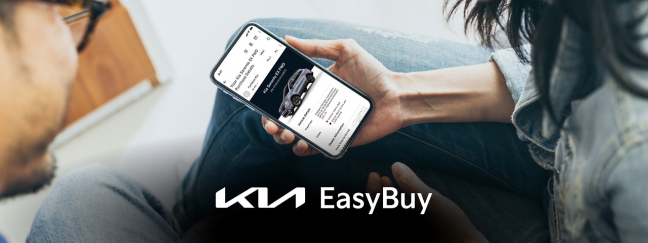Two people looking at a phone that has the 2023 Kia Sorento purchase details on the screen
