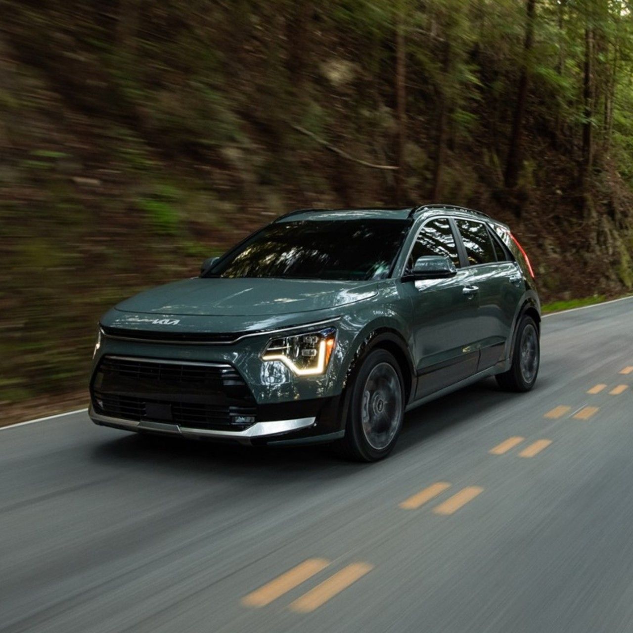 2026 Kia Niro Hybrid, three-quarter front view, driving on a road in the mountains