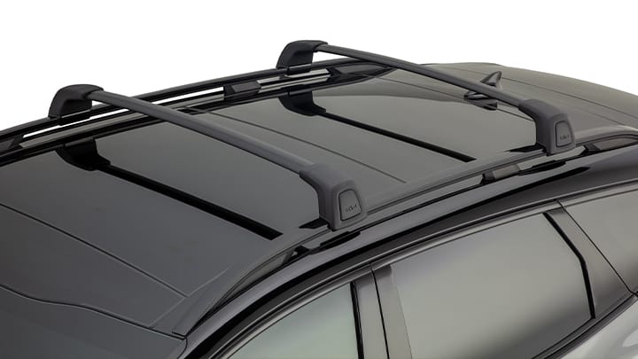 Close-up of Kia roof rack cross bars mounted on the roof of a black SUV, highlighting cargo-carrying accessories and sleek exterior design.