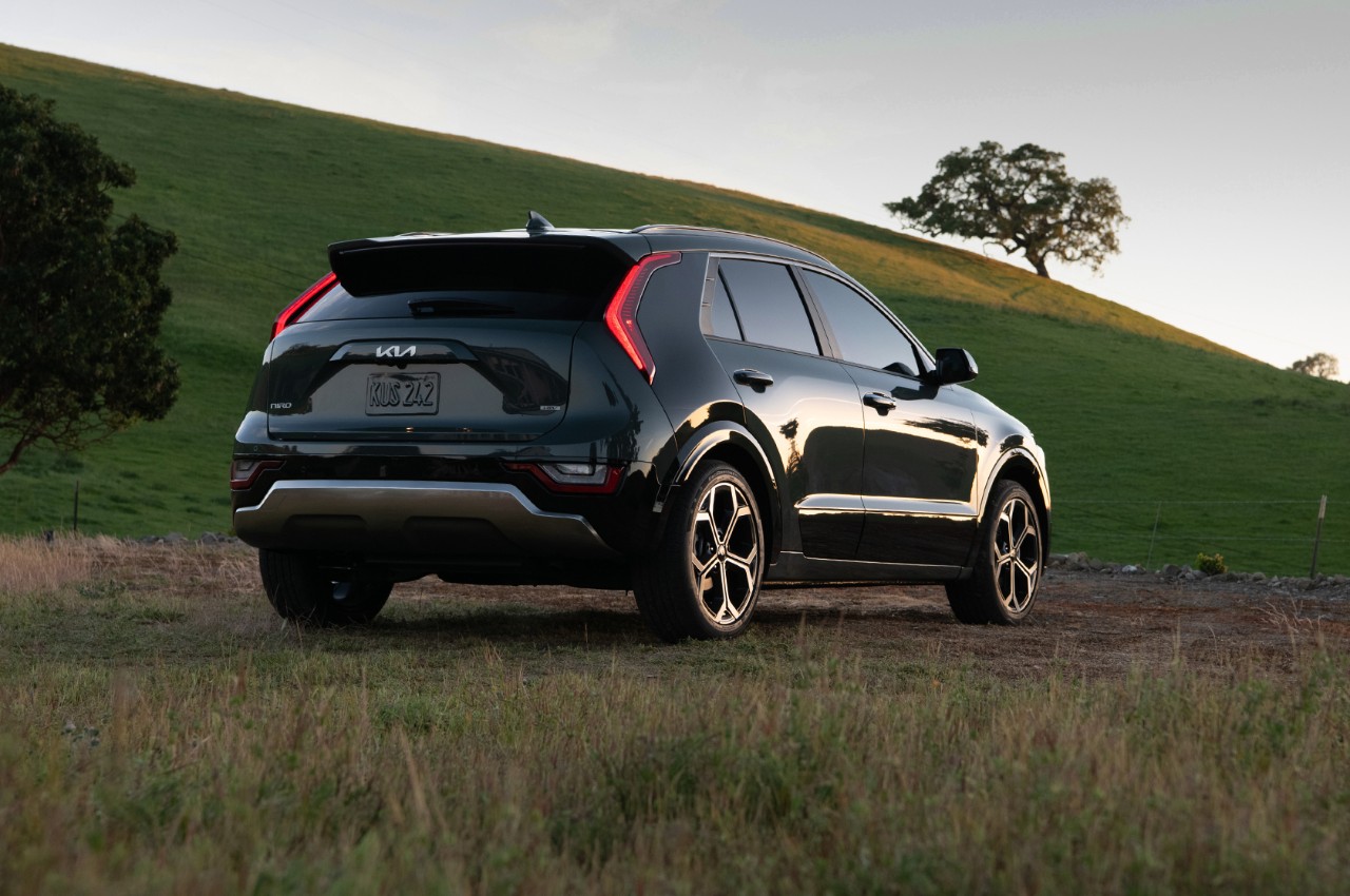 2023 Kia Niro Hybrid Parked In Front Of A Grassy Hill Rear Three-Quarter View
